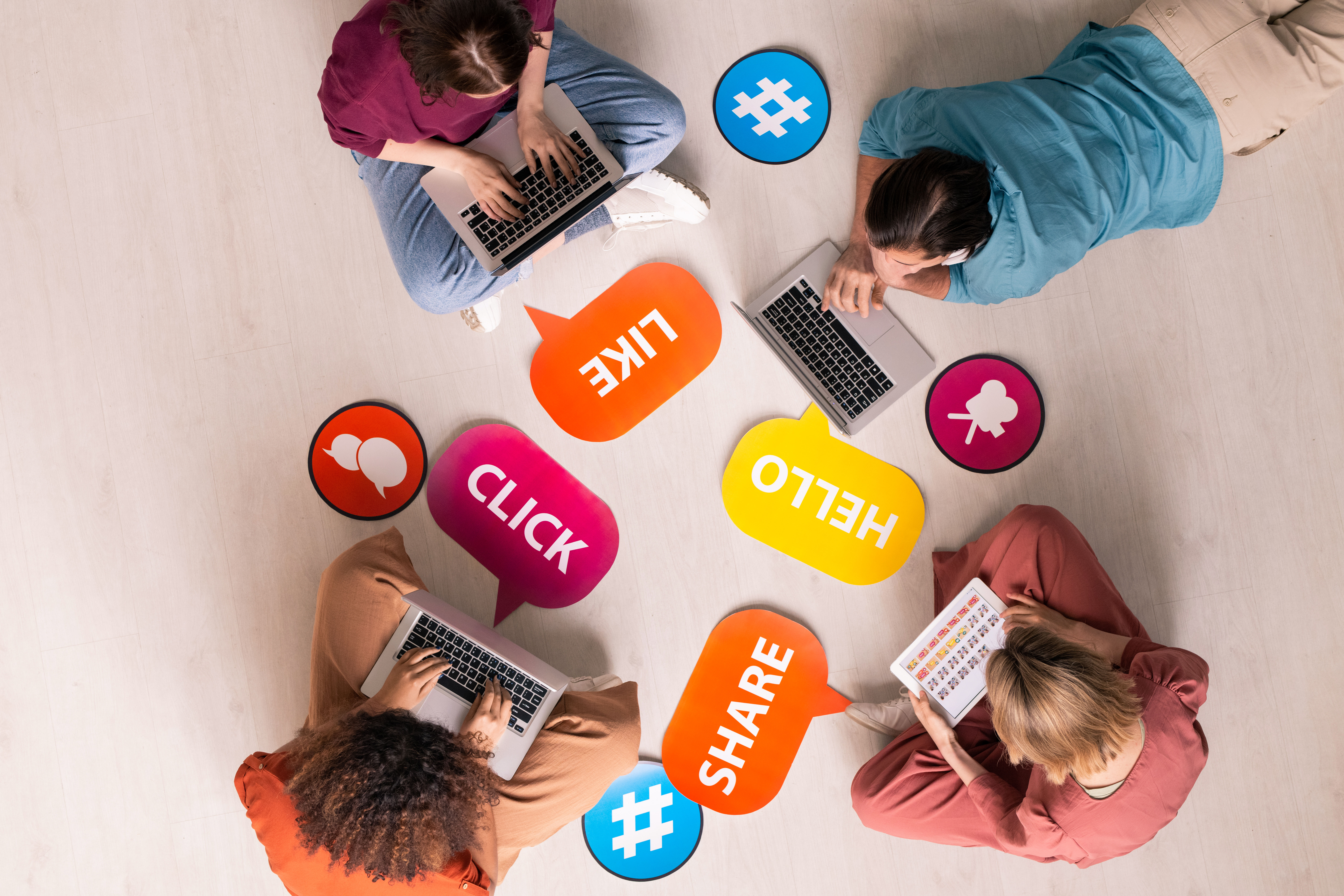 Overview of four young contemporary friends using mobile gadgets on the floor image de personnes sur les réseaux sociaux